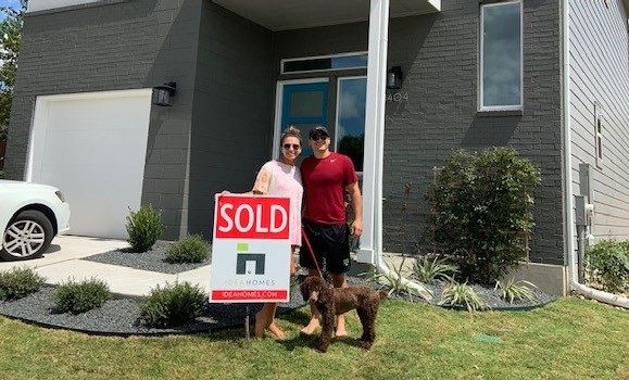 homeowners holding a "sold" sign moving into their new Austin home