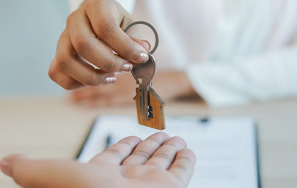 Realtor handing a set of house-shaped keys to a new homebuyer.